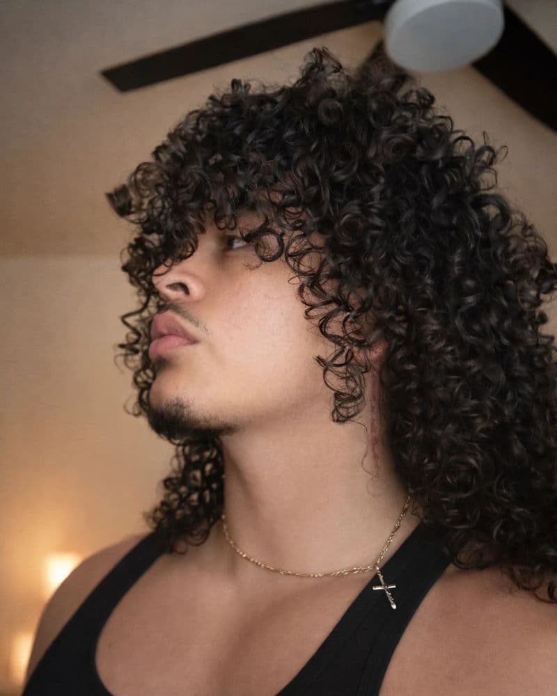 Jeovany Gutierrez in profile, long defined 3A curls in warm light.